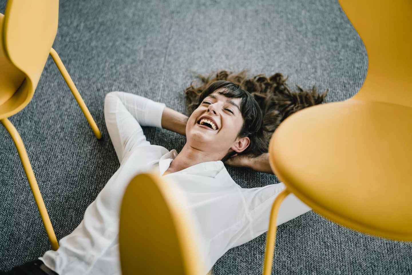 En person ligger på golvet i ett konferensrum och skrattar avslappnat.