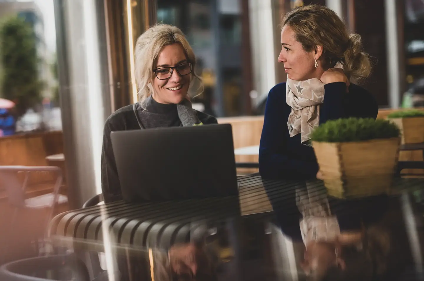 Två personer i trevligt samtal med var sin laptop.