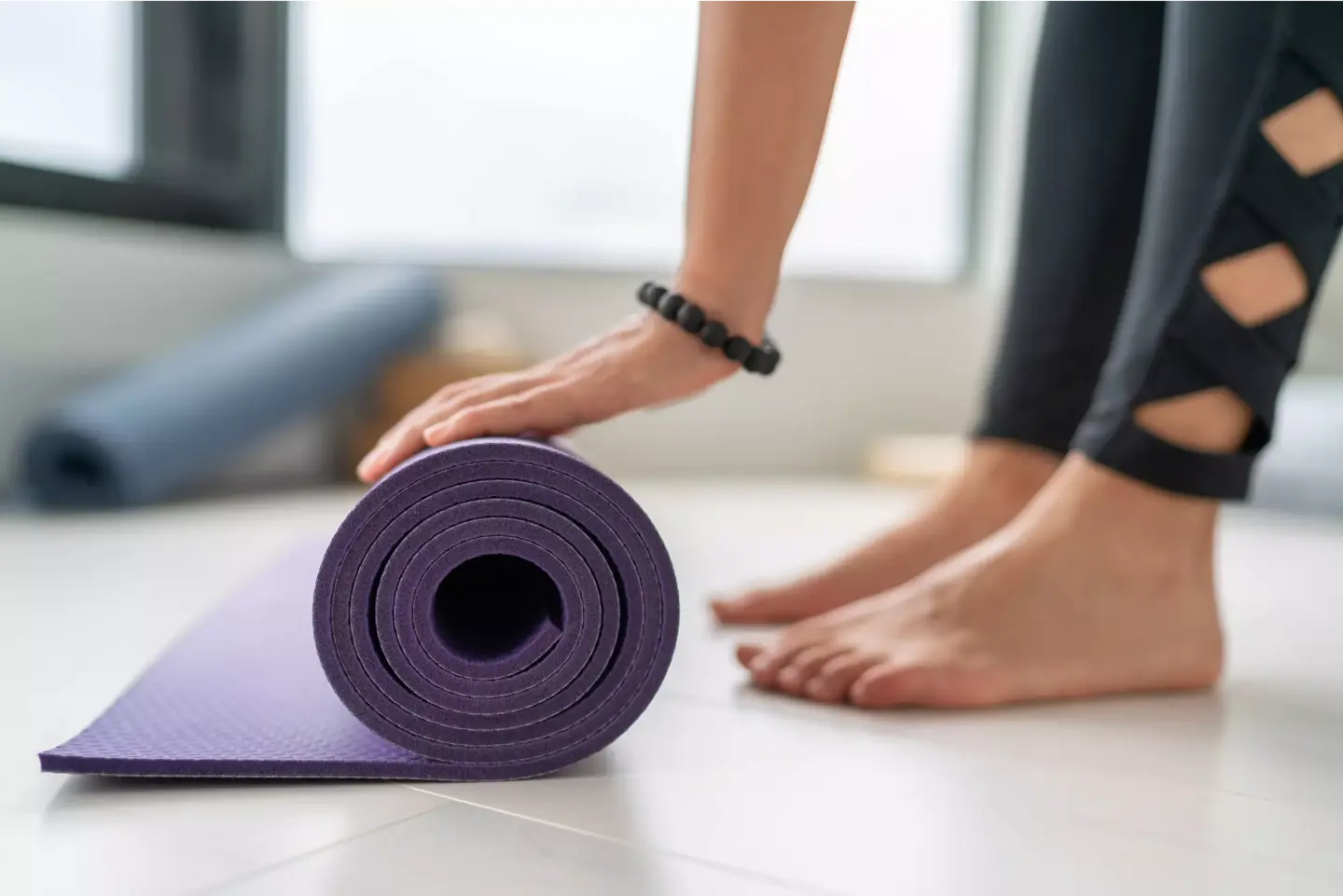 Närbild av händer och fötter på en person som rullar ut en yogamatta.