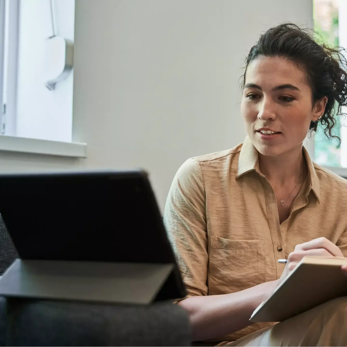 Inspirerad kvinna deltar i digitalt möte från sitt eget vardagsrum.