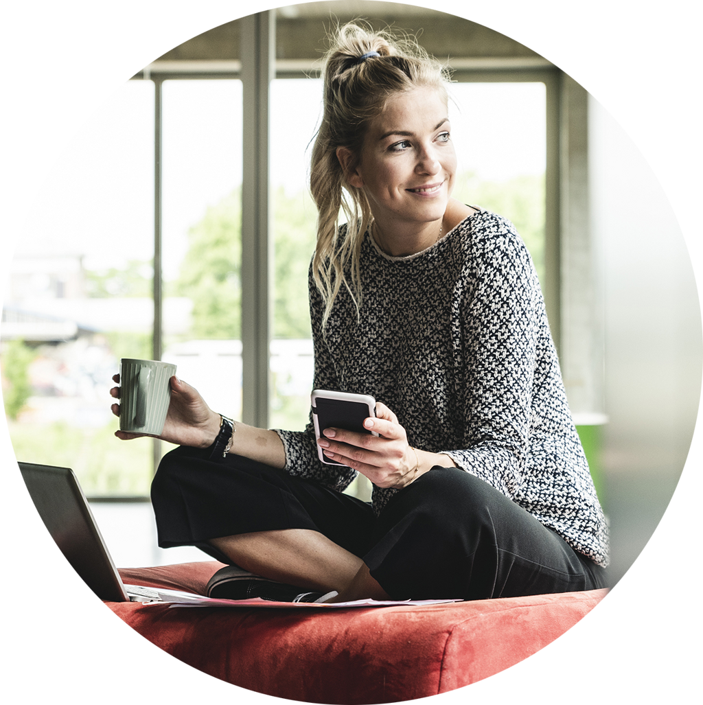 Kvinna på arbetet på sittpuff med dator och kaffe